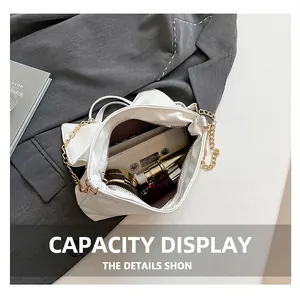 Detailed interior of white pleated chain bag showing phone, lipstick and makeup storage