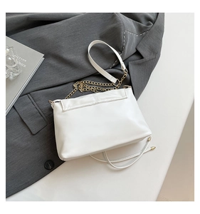 Détail d'un sac à bandoulière en cuir blanc avec chaîne dorée sur fond minimaliste