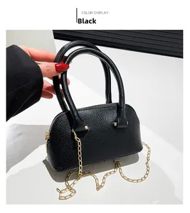 Detail of black lychee grain leather mini shell bag with gold chain and round handles