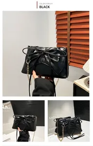 Detail of black bow-knot shoulder bag with elegant light gold chain strap detail