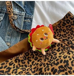 Dettaglio di un ciondolo a forma di burger in peluche ricamato su borsa leopardata