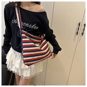 Détail du sac cabas en toile rayée avec dentelle et nœud porté par un mannequin