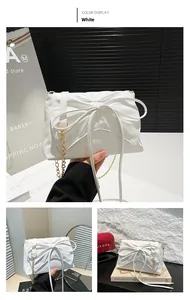 Close-up of white crossbody bag with large pleated bow and golden chain strap
