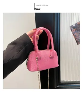 Close-up of pink litchi grain leather shell bag with golden chain and handle details