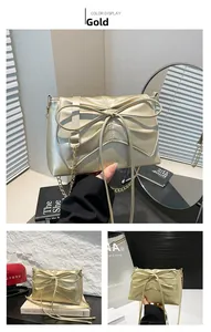 Detailed view of the large bow decoration and gold chain strap on the metallic handbag