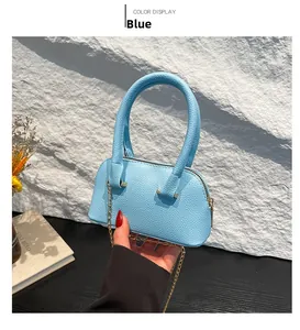Detail of light blue lychee pattern mini shell bag with gold chain strap in hand