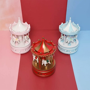 Three colorful wooden carousel music boxes in pink, red, and blue for Christmas gifts