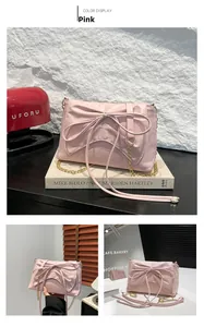 Close-up of pink bow decoration and gold metal chain on soft PU leather crossbody bag