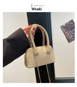 Close-up of khaki litchi grain shell bag with gold chain strap and top handle