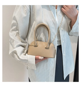 Detailed macro of beige lychee grain leather shell bag with gold chain strap