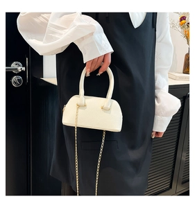 Close-up of white shell-shaped handbag with gold chain strap and lychee texture