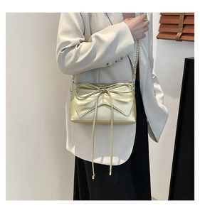Detail of elegant champagne gold chain bag with a large bow and metallic shoulder strap