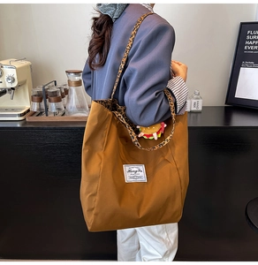 Dettaglio borsa tote marrone in tela con tracolla leopardata e ciondolo hamburger