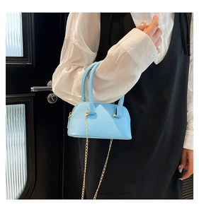 Detail of light blue shell bag with lychee texture and gold chain strap on model