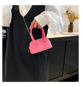 Gros plan d'un sac coquillage rose vif avec texture litchi et chaîne dorée fine