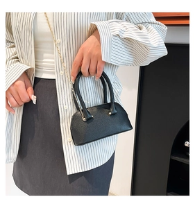 Detail of black lychee grain mini shell bag with golden chain and round handles