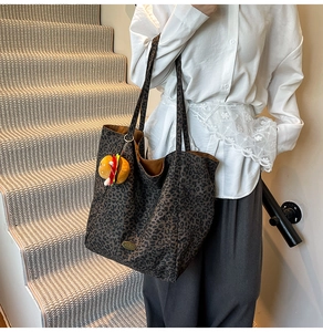 Dettaglio della borsa tote in tela leopardata scura con un ciondolo a forma di hamburger