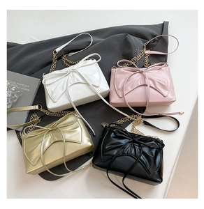 Detail of four stylish pleated bow shoulder bags in white, pink, gold, and black colors