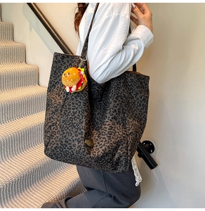 Dettaglio della borsa tote leopardata in tela con un ciondolo a forma di burger di peluche