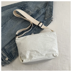 Detail of white textured fabric messenger bag with adjustable nylon shoulder strap