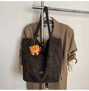 Dettaglio della borsa tote in tela leopardata con ciondolo a hamburger e logo in metallo
