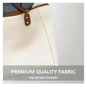 Close-up of contrast brown strap and gold rivet detailing on cream faux leather tote bag