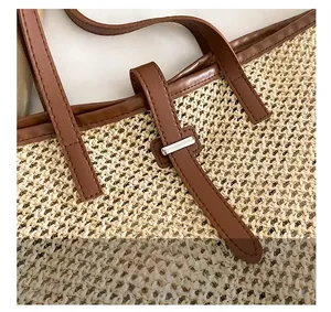 Close-up of premium silver hardware and brown faux leather handle on a straw woven tote bag