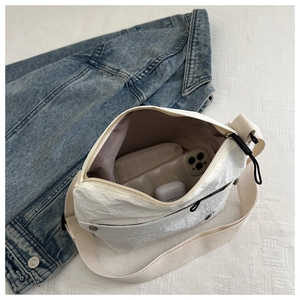 Internal view of a white nylon crossbody bag showing storage space for phone and accessories