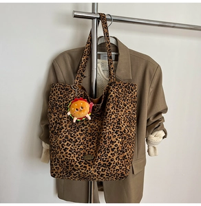 Dettaglio della borsa tote leopardata in tela con ciondolo burger in peluche e logo in metallo