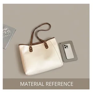 Close-up of beige tote bag with brown handles and gold hardware in a chic office setting