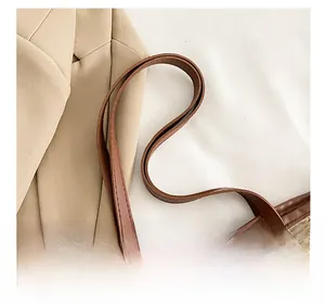 Detail of woven straw tote bag with brown faux leather handles and fine stitching