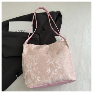 Detail of pink floral embroidery on a chic tote bag with satin finish base texture