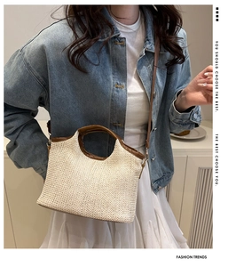 Detail of woven straw tote bag with brown leather handles and a matching crossbody strap