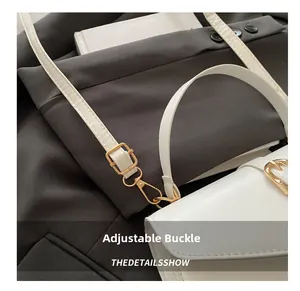 Detail view of adjustable white leather strap with golden metal buckle on crossbody bag