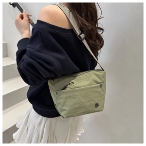 Detail view of water-resistant green nylon crossbody bag with zipper and rivets