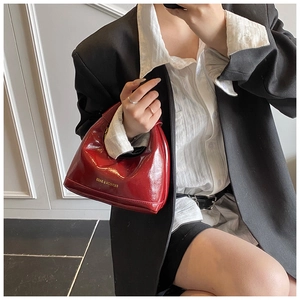Sac à main chic en cuir verni rouge porté avec un blazer noir et une chemise blanche