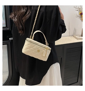 Chic quilted beige mini box bag with gold chain strap and floral logo shown in setting