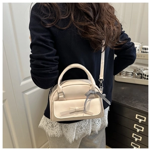 Detail of cream bow Boston bag with checkered ribbon handle on a shoulder strap