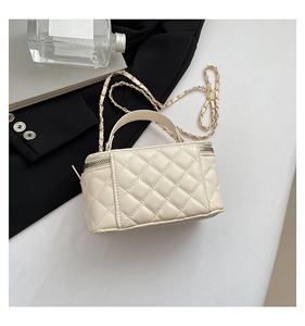 Close-up of cream quilted mini bag with dual zippers and elegant gold chain strap detail