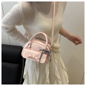 Close-up of pink bow handbag featuring a black and white checkered ribbon detail