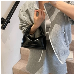 Close-up of a black patent leather crescent hobo bag with reflective mirror finish