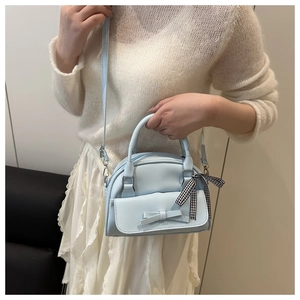 Detail of light blue bow handbag featuring a black and white checkered ribbon accessory