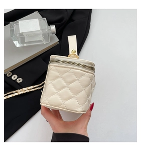 Detail showing creamy quilted leather texture and golden chain strap on a small bag