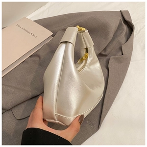 Détail d'un sac hobo blanc perle en cuir froissé avec ornements dorés sur veste grise
