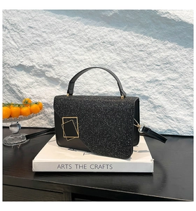 Close-up of black crossbody bag with sequin flap and golden dual rectangular metal lock