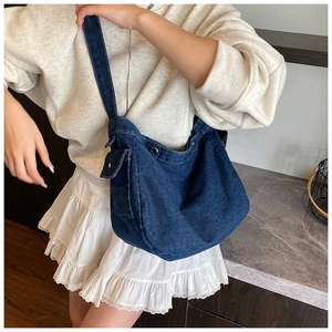 Detail view of large blue denim hobo bag featuring wide shoulder strap and side metal buckle