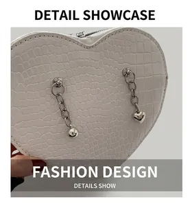 Detail of white heart-shaped bag with crocodile pattern and silver metal heart chains