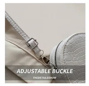 Detail of adjustable metal buckle on white crocodile pattern leather shoulder bag