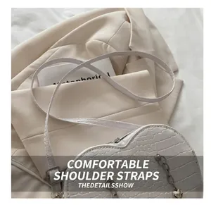 Close-up of white heart-shaped bag with crocodile texture and silver chain detail