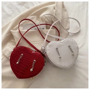 Detail of red and white heart-shaped crossbody bags with faux crocodile texture and chain